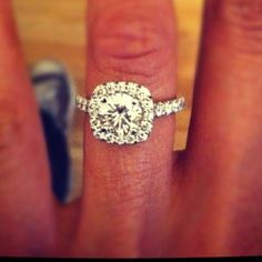 a woman's hand with a diamond ring on top of her finger and an engagement ring in the middle