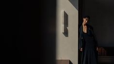 a woman in a long black dress standing next to a wall