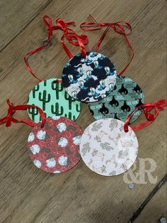 four christmas ornaments with red ribbon on wooden floor