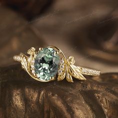 a fancy ring with an aqua green stone surrounded by white and yellow diamonds on top