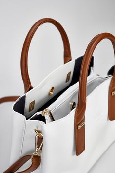 The Porcelain White Hudson Tote is sleek and stylish with a classic brown strap. Crafted with a luxurious Porcelain white leather, its timeless design is ideal for any occasion. It provides the flexibility to be worn as a tote or crossbody bag. Material: Genuine Soft Vegan Leather Dimensions : 33 L x 14 w x 23 h Pockets: 6 Interior compartments Straps : 2 chocolate brown handles & 1 chocolate brown crossbody strap Locks: 2 snap gold locks & Middle zipper Color : Porcelain White Tote Shoulder Bag With Adjustable Handle, Chic White Satchel With Adjustable Handle, White Satchel With Leather Handles, White Leather Top Handle Shoulder Bag, White Crossbody Shoulder Bag With Leather Handles, Chic White Shoulder Bag With Adjustable Handle, White Satchel With Double Leather Handles, White Leather Satchel With Leather Handles, White Bags With Adjustable Handle For Everyday Use