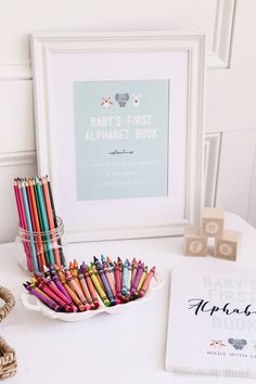 the baby's first alphabet book is next to some colored crayons in a bowl