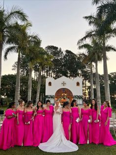 a group of women in pink dresses standing next to each other near some palm trees