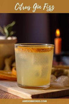 a glass filled with liquid sitting on top of a wooden cutting board next to an orange slice