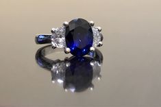 Dekara Designs Collection Metal- 90% Platinum, 10% Iridium. Stones- 1 Natural Untreated 3.88 Carat Oval Cut Ceylon Blue Sapphire. 2 Moon Cut Diamonds, F-G Color VS1 Clarity 0.77 total carats This ring is a size 6, but could be sized up or down a few sizes. This ring could be made in your specific size within 5-10 business days. Could take a little more time due to the ceylon sapphire being a rare stone. The sapphire may be a bit smaller or bigger. We can make the same design in a smaller or bigg Classic Blue Sapphire Diamond Ring, Formal Blue Sapphire Ring Gia Certified, Blue Gia Certified Diamond Ring For Formal Occasions, Blue Oval Sapphire Ring With Vvs Clarity, Oval Blue Sapphire Ring With Vvs Clarity, Elegant Blue Sapphire Three Stone Ring, Formal Blue Lab-created Sapphire Diamond Ring, Luxury Blue Three Stone Ring, Blue Three Stone Round Cut Diamond Ring