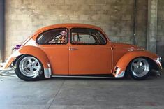 an orange vw bug is parked in a garage