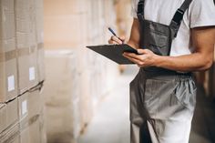 a man in overalls writing on a clipboard