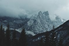 the mountains are covered in clouds and trees