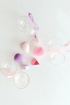 several wine glasses with pink, purple and white confetti in them on a white surface