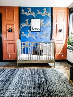 a white crib in front of a blue and orange wall with an animal print on it