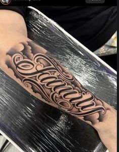 a man's arm with the word tattoo on it and clouds in the background