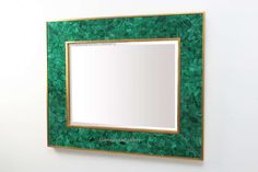 a mirror mounted to the side of a wall with green leaves on it's frame