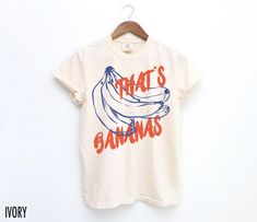 Go bananas for vintage style with our "That's Bananas" retro inspired graphic tee. We use professional quality DGT printing on all our apparel. Direct-to-garment, or DTG, is a high quality printing method that sprays ink directly onto the garment so there is no peeling or cracking. This fabulous graphic will be printed on a Comfort Colors Unisex T-Shirt. Please refer to the size charts in the images for the best fit.  Estimated Production Time: 1-5 days Estimated Shipping Time: 2-5 days 100% cot Unisex Summer Tops With Graphic Design, Unisex Graphic Tops For Summer, Unisex Graphic Design Summer Tops, Funny Graphic Summer Tops, Funny Graphic Design Tops For Summer, Unisex Retro Summer T-shirt, Summer Graphic Print Unisex Shirt, Retro Graphic Design Shirt For Summer, Retro Cotton T-shirt With Funny Print