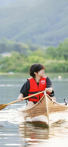 a man in a red life jacket paddling a canoe