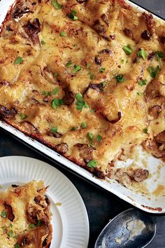 a casserole dish with meat and cheese in it on a plate next to a fork