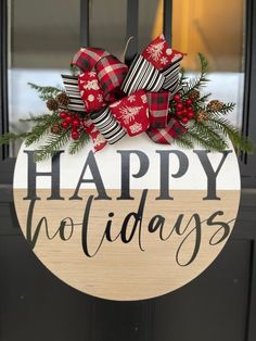 a wooden sign that says happy holidays hanging on a door with pine cones and ribbon