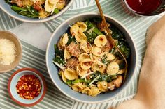 two bowls filled with pasta, meat and veggies on top of a table