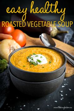 a bowl of roasted vegetable soup with sour cream on top and fresh vegetables in the background