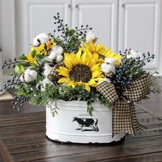 a white bucket filled with lots of yellow flowers and cotton floss sitting on top of a wooden table