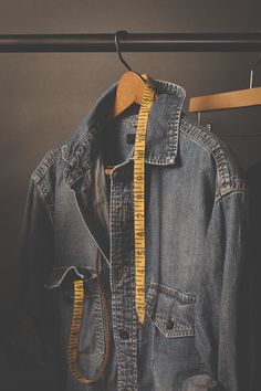 an old jean jacket hanging on a clothes rack with a measuring tape around it's waist