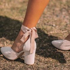 the legs and ankles of a woman wearing high heeled shoes with bows on them