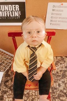 a little boy wearing glasses and a tie sitting on a chair with his feet crossed