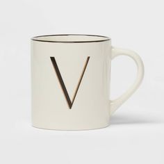 a white and black coffee mug with the letter v on it's front side