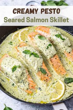 creamy pesto salmon skillet in a pan with lemons and basil on the side