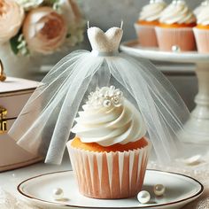 a cupcake with white frosting and a veil on top is sitting on a plate