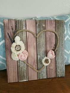 a wooden sign with flowers on it sitting on a table next to a blue pillow