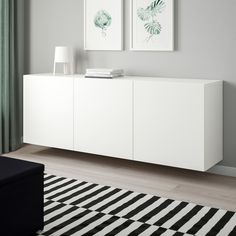 a living room with two pictures on the wall and a black and white striped rug