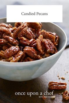 a bowl filled with candied pecans on top of a wooden table