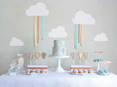 a table topped with cakes and cupcakes under clouds