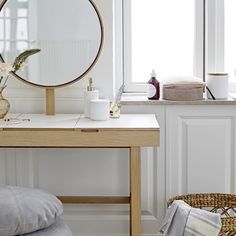 a white desk with a mirror, vase and other items on it in front of a window