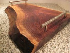 a wooden cutting board with metal handles on a counter