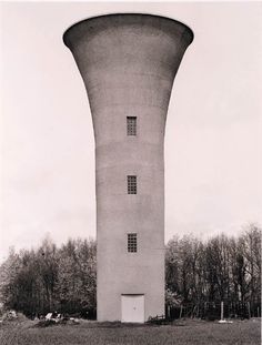 an old photo of a water tower in the middle of a field with trees around it