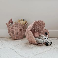 two wicker baskets with stuffed animals in them sitting on the floor next to each other