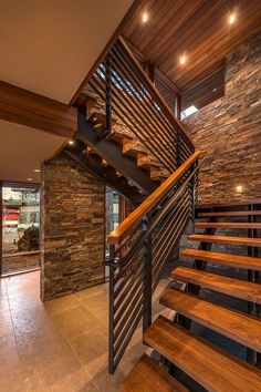 a wooden stair case next to a stone wall and wood flooring in a home