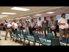 a group of men standing around each other holding pink and white balloons in front of them