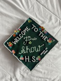 a green graduation cap that says welcome to the show h s