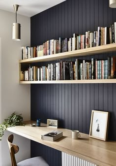 a home office with bookshelves, desk and chair in front of the window