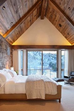 a large bed sitting under a wooden ceiling in a bedroom next to a sliding glass door