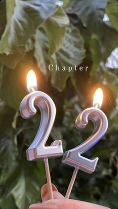 someone is holding a birthday candle with the number two on it