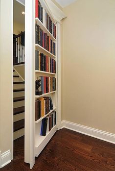 a book shelf filled with lots of books next to a stair case