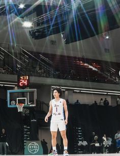 a man standing on top of a basketball court with a ball in his hand and people watching from the bleachers