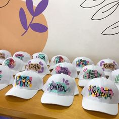 many hats with words on them sitting on top of a wooden table in front of a wall