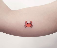 a small crab tattoo on the left upper arm and right lower arm, which has an orange crab on it's side