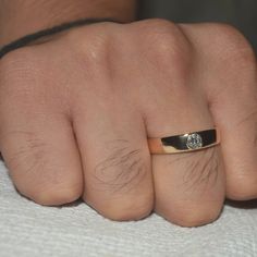 a person's hand with a ring on it and a diamond in the middle