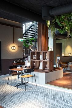 the interior of a restaurant with tables, chairs and plants hanging from the ceiling above