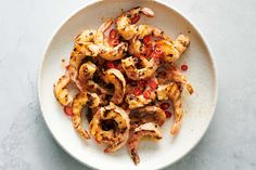 a white plate topped with cooked shrimp and peppers on top of a marble countertop